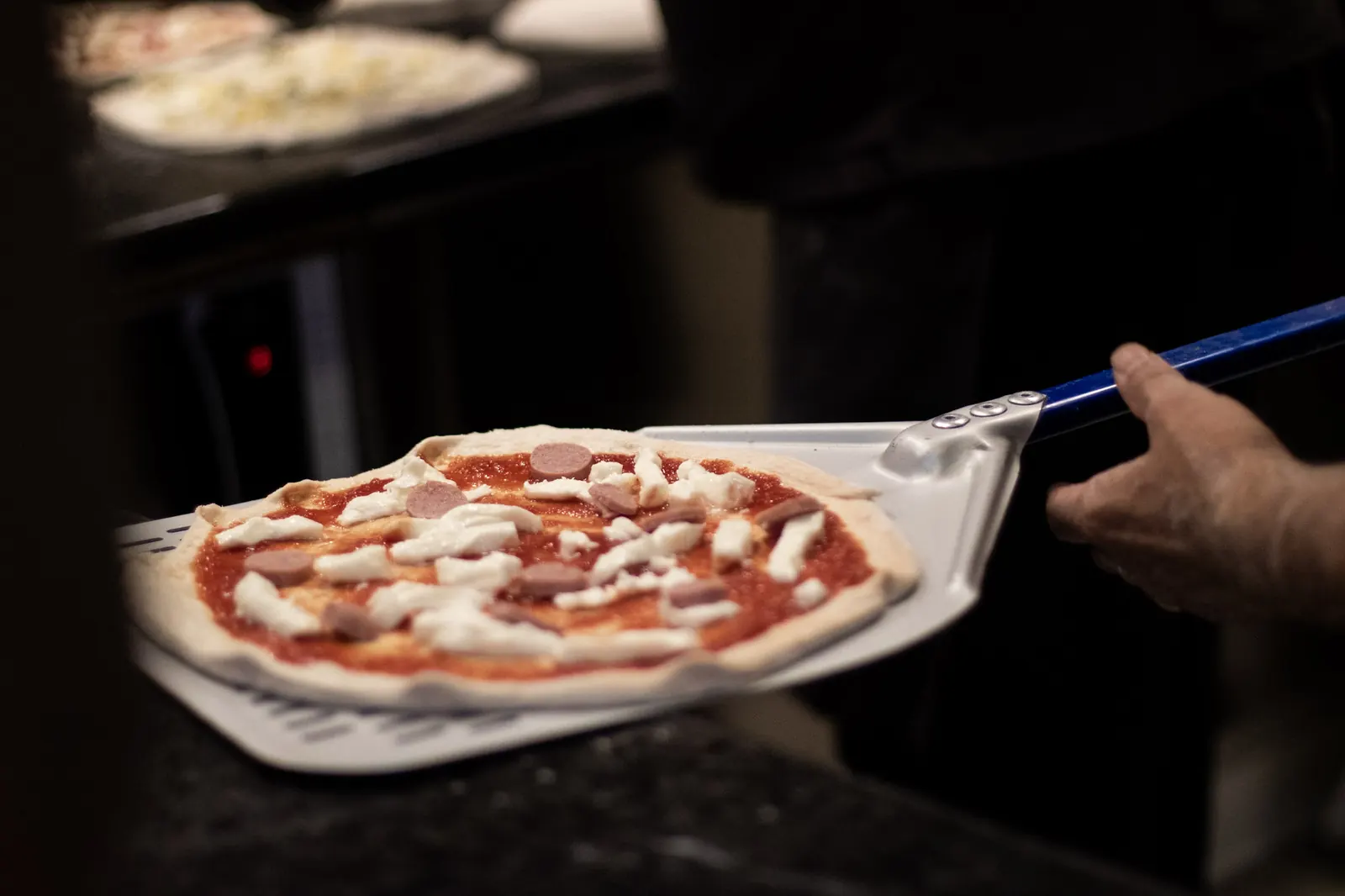 Una pizza tonda sulla pala, un attimo prima di entrare in forno